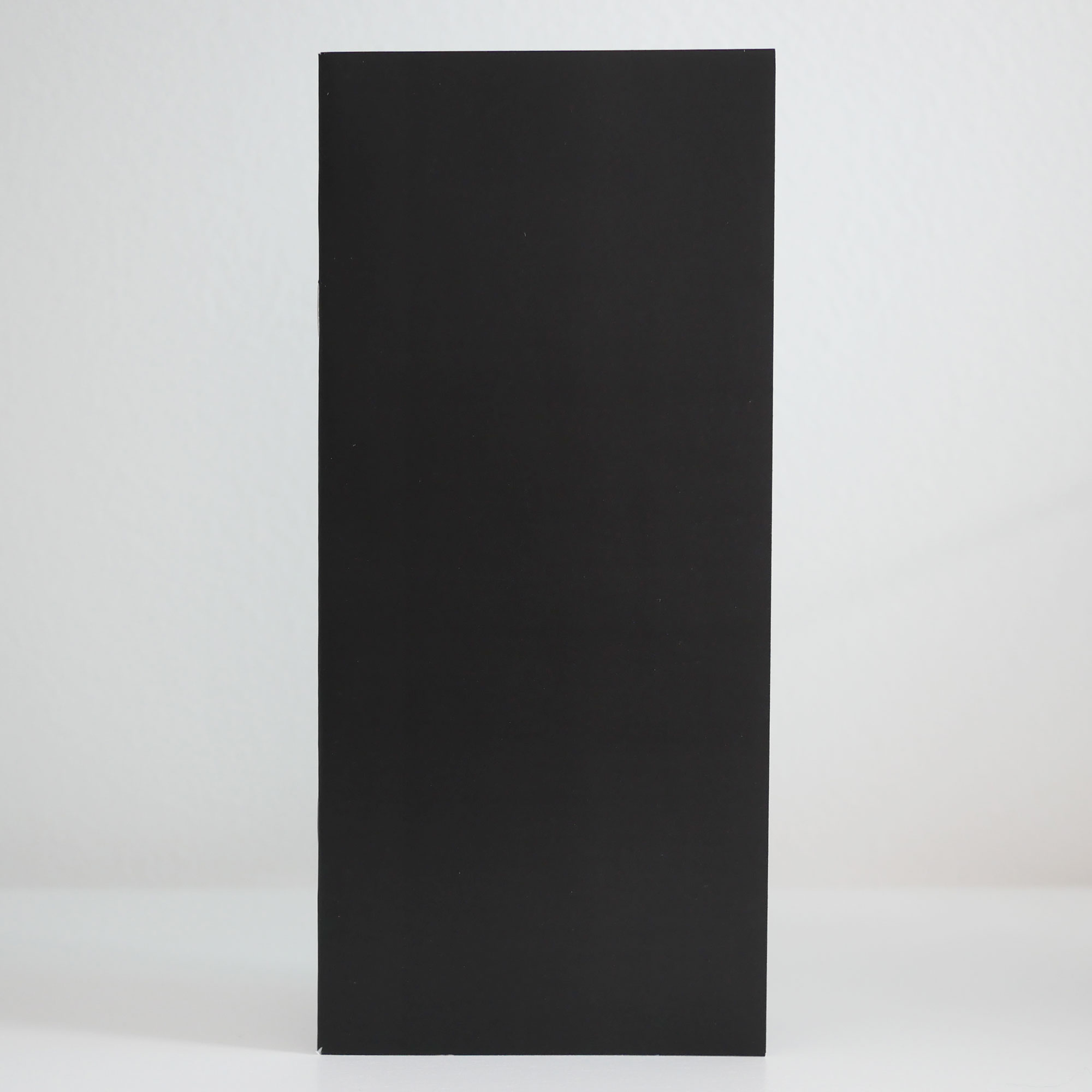 A black, rectangular zine stands like a black monolith.
